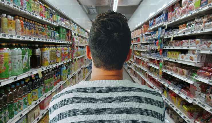 uomo di spalle in una corsia del supermercato